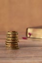 Stack of coins and holy bible book with golden pages on a wooden background, vertical shot, copy space