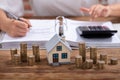 Stack Of Coins And House Model On Desk Royalty Free Stock Photo