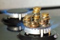 Stack of coins on kitchen stove, blue flame of natural gas burner. Expensive utilities