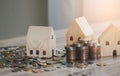 Stack of coins money with wood house model on table and sunlight, Business Growth concept, Financial risk. for plan saving money