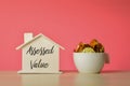 Stack of coins in a mug and toy house model with text ASSESSED VALUE