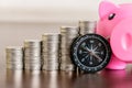 Stack of coins with piggy bank and compass on wood table Royalty Free Stock Photo