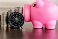 Stack of coins with piggy bank and compass on wood table Royalty Free Stock Photo