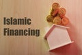 Stack of coins and toy model house with text ISLAMIC FINANCING