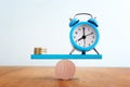 Stack of coins and vintage clock balance on seesaw Royalty Free Stock Photo