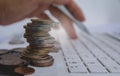 Stack coins on white laptop and finger press button on keyboard. Royalty Free Stock Photo