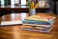 stack of colorful art journals on an oak desk