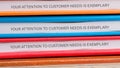 A stack of colorful binders displays the phrase, demonstrating a commitment to customer service excellence. This