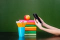 Stack of colorful books with electronic book reader near empty green chalkboard. Sample for text Royalty Free Stock Photo