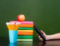 Stack of colorful books with electronic book reader near empty green chalkboard. Sample for text Royalty Free Stock Photo