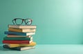 Stack of colorful books with glasses on top rests on smooth surface against light green background. Image suggests learning, Royalty Free Stock Photo