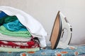 Stack of colorful clean towels  on grey background. Ironing clothes on ironing board. Stack of clean towels on table. Royalty Free Stock Photo