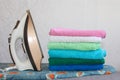 Stack of colorful clean towels on grey background. Ironing clothes on ironing board. Stack of clean towels on table. Royalty Free Stock Photo