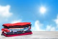 Stack colorful clothes. Closeup of a pile of colorful t-shirts or shirts on a bright table against abstract blurred sunny blue sky Royalty Free Stock Photo