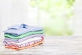 Stack colorful clothes. Pile of folded cotton shirts on a bright table with space for your display product montage against