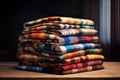 Stack of colorful fabrics (bedsheets, towels plaids etc.) on a wooden table in home interior