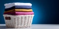 Stack of colorful folded clothes neatly arranged in a white wicker basket on a white surface with a blue gradient background Royalty Free Stock Photo