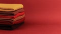 Stack of colorful folded sweaters on brown maroon background with copy space. Royalty Free Stock Photo