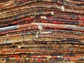 Stack of colorful handmade antique Oriental style rugs and carpets background texture pattern