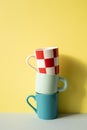 Stack of colorful mug cups on gray table. yellow wall background Royalty Free Stock Photo