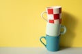 Stack of colorful mug cups on gray table. yellow wall background Royalty Free Stock Photo