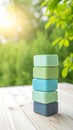 Stack of colorful pastel sponges arranged on a wooden surface with a soft green blurred background and sunlight. Royalty Free Stock Photo