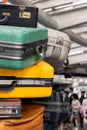 Stack of colorful travel suitcases at terminal with tourist people in the background, Holiday vacation trip