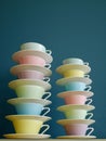 Stack of colorful vintage tea and coffee cups against petrol background. Vertical. Royalty Free Stock Photo