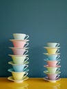 Stack of colorful vintage tea and coffee cups on yellow table against petrol background. Royalty Free Stock Photo