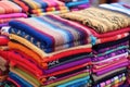 a stack of colorful woven rugs at a market stall