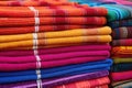 a stack of colorful woven rugs at a market stall