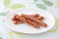 Stack of cooked sausages on a plate on tablecloth