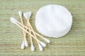 Stack of cotton pads and heap of wood stick cotton buds on a bast fiber mat background. Plastic free hygiene supplies, beauty