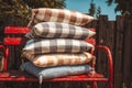 Stack of cozy checked cushions on a red bench outdoors Royalty Free Stock Photo
