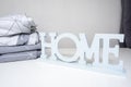 A stack of cozy home textile in shades of gray bed linen, bedding with the sign home near it Royalty Free Stock Photo