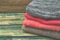 Stack of cozy knitted sweaters. A pile of warm sweaters on a wooden table on green rustic background. Autumn and winter clothes. Royalty Free Stock Photo