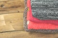 Stack of cozy knitted sweaters. A pile of warm sweaters on a wooden table on rustic background. Autumn and winter clothes. Copy