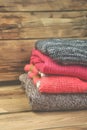 Stack of cozy knitted sweaters. A pile of warm sweaters on a wooden table on rustic background. Autumn and winter clothes. Copy