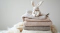 Stack of cozy knitted sweaters with a plush bunny on top