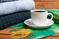 Stack of cozy knitted warm sweater and a scarf . Sweaters in retro Style and a Cup of coffee. The concept of warmth and comfort Royalty Free Stock Photo