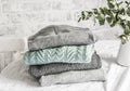 Stack of cozy winter autumn sweaters pullovers on the table on a light background