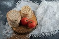 Stack of crispbread, tomatoes and raw buckwheat on wooden piece