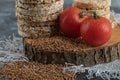 Stack of crispbread, tomatoes and raw buckwheat on wooden piece