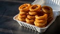 Stack of Crispy Onion Rings in Takeout Container Royalty Free Stock Photo