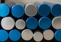 A stack of cylindrical pipes with metallic blue and silver ends is displayed, arranged in a Royalty Free Stock Photo