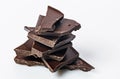 A stack of dark cracked chocolate on a white background. Pieces of bitter chocolate. Food photography. Close-up. Copy space