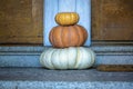 Stack of decorative autumn pumpkins or squash with orange and white color on stoop or front door stairway