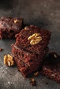Stack of delicious brownie pieces with hazelnuts on top on dark background close up Royalty Free Stock Photo