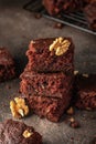 Stack of delicious brownie pieces with hazelnuts on top on dark background close up Royalty Free Stock Photo