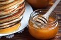 Stack of delicious, homemade pancakes with honey on white plate on wooden background. Healthy breakfast, close up. Pancake`s Day. Royalty Free Stock Photo